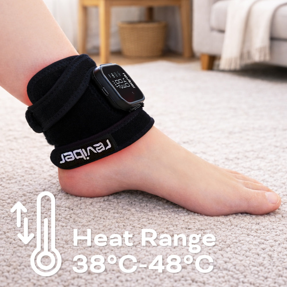A person wears a black Reviber Infrared Light Therapy Pad with digital display on their ankle, sitting on a light floor. Text overlay: “Heat Range 38°C-48°C” with a thermometer icon. Brand: Reviber. Pain relief wearable for home use.