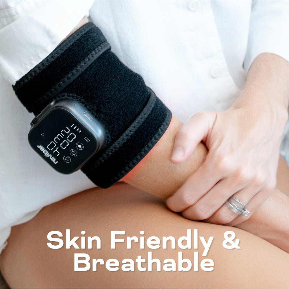 A person wearing the Reviber Infrared Light Therapy Pad by Reviber on their wrist, dressed in a white shirt with a silver ring. Text reads: Skin Friendly & Breathable.
