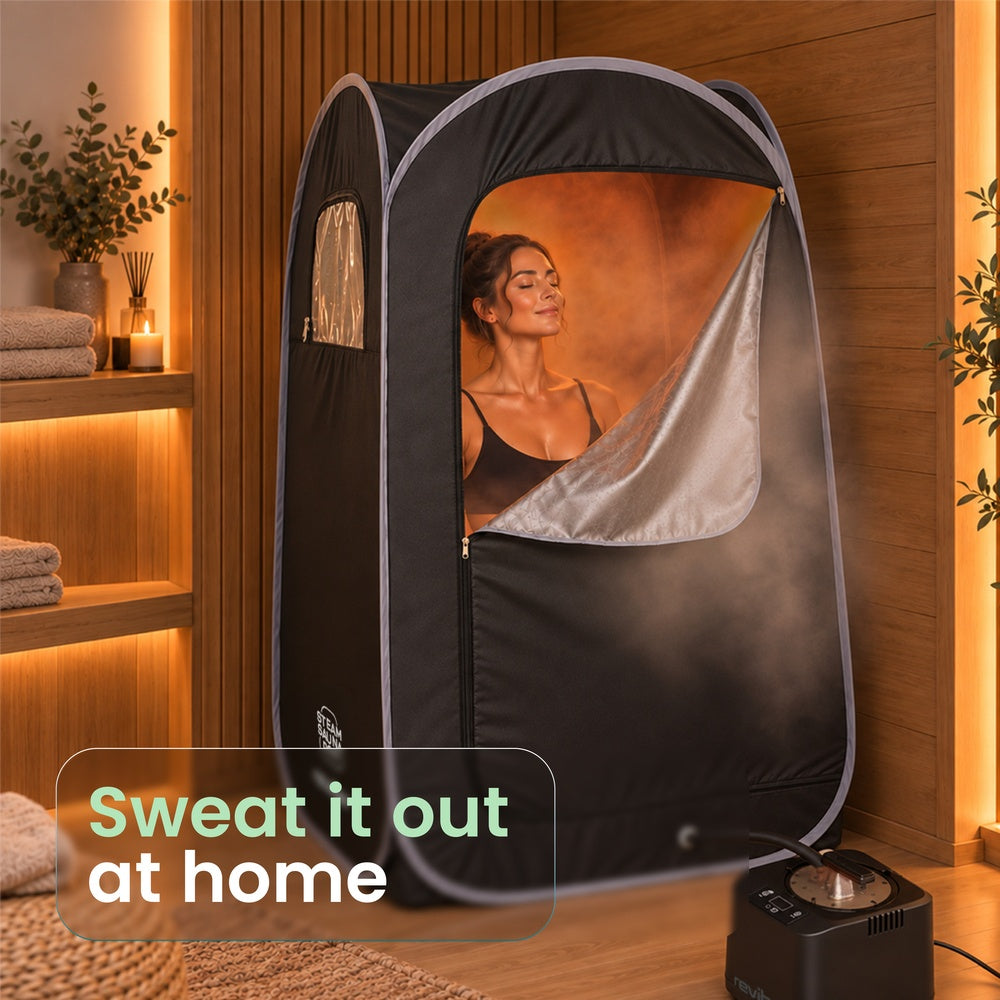 A woman sits inside a Reviber Steam Sauna Pod for at-home relaxation with a steam generator unit on the floor nearby and a text overlay that reads: Sweat it out at home.