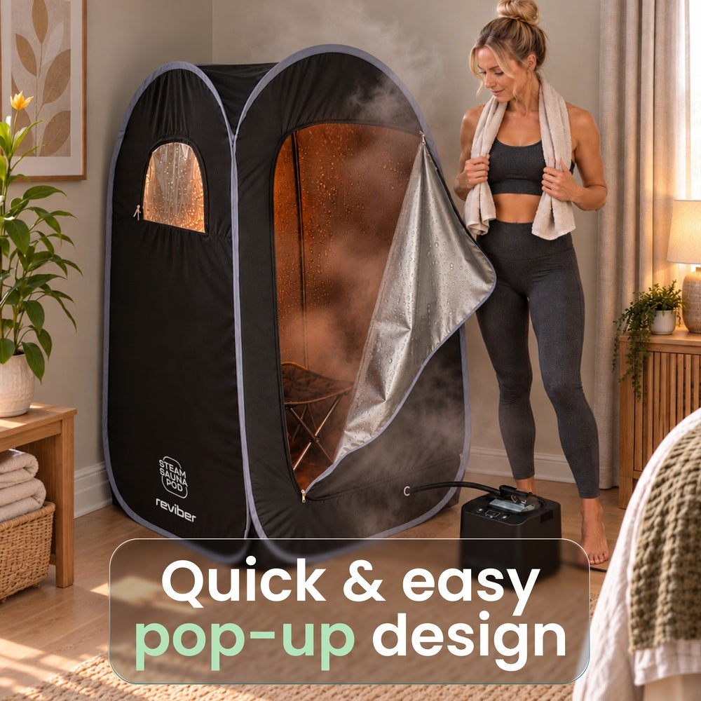 A person stands next to an open Reviber Steam Sauna Pod, which is filled with steam for at-home relaxation.