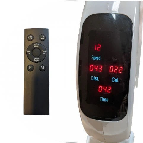 A Reviber Mini Bike Pro Remote Control in black, featuring multiple buttons, lies next to the electronic display of the compact Reviber Mini Bike Pro showing red numbers for speed, distance, calories, and time.